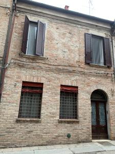 ceglany budynek z czterema oknami i drzwiami w obiekcie InCastrum - la soffitta in centro w mieście Ferrara