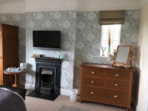 a bedroom with a fireplace and a tv on the wall at Grange House Bed & Breakfast in Lowdham