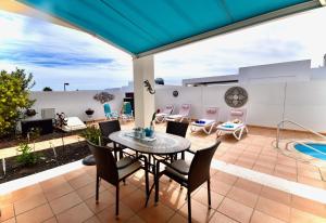 patio ze stołem i krzesłami oraz basenem w obiekcie Casa Vivien w mieście Playa Blanca
