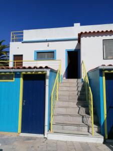 uma casa branca com portas azuis e escadas em Casa do Lado na Carrapateira