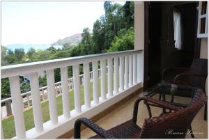 a porch with two chairs and a balcony with a view at Exotic Guest House in Anse Possession