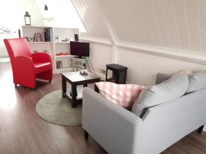 a living room with a white couch and a red chair at B&B Alkmaars Toppunt in Alkmaar