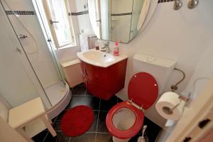 uma casa de banho com um WC vermelho e um lavatório. em Villa MT em Posedarje
