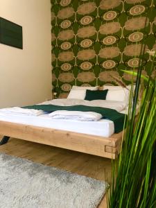 a bed in a bedroom with a green wall at Boróka Apartman Belváros in Veszprém