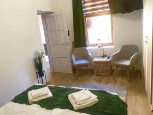 a bedroom with a bed with two chairs and a window at Boróka Apartman Belváros in Veszprém