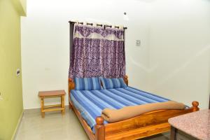 1 dormitorio con cama de madera y cortina en Thirumalai Home Stay - Group & Family Stay Room VL Swami Malai Temple, en Kumbakonam