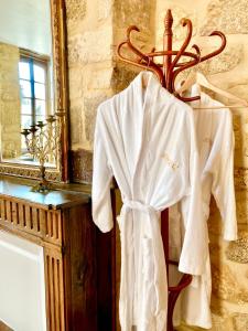 ein weißer Bademantel hängt an einem Kleiderständer neben einem Spiegel in der Unterkunft Les Petits Cousins Du Québec - Chambres D’hôtes à Domme in Domme