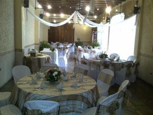 a room full of tables and chairs with white tablecloths at Hotel Posada de Don José in Retalhuleu