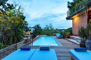 a backyard swimming pool with a wooden deck and a balcony at Ruang Tekuni in Legian