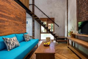 a living room with a blue couch and a wooden table at Ruang Tekuni in Legian
