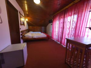 Zimmer mit einem Bett, einem Tisch und einem TV in der Unterkunft Pensiunea Melinda in Petroşani
