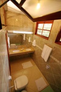a bathroom with two sinks and a toilet and a mirror at Pousada e Residencial Villafranca in Boicucanga