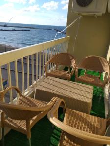 drie stoelen en een tafel op een balkon met uitzicht op de oceaan bij Sea View Sidi Bisher - in front of Sidi Bisher Mosque - Best Choice for Families - only Families- No Solo - No unmarried please in Alexandrië