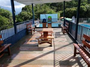a deck with benches and a table and a pool at Finca Campestre Piscina Privada Anapoima in Anapoima