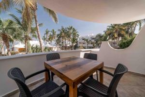 einen Tisch und Stühle auf einem Balkon mit Palmen in der Unterkunft Hotel & Suites El Moro in La Paz