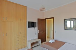 a bedroom with a bed and cabinets and a tv at VILLA KONSTANTINOS 6 bedrooms in Egina