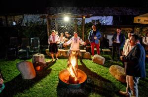 a group of people standing around a fire pit at Pensiunea Curtea lui Toader in Simioneşti