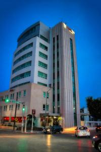 a tall building with cars parked in front of it at Hotel Vista Inn Premium in Tuxtla Gutiérrez