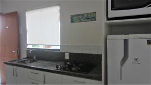 a kitchen with a sink and a white refrigerator at Residencial Marbella in Bombinhas