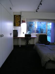 a bedroom with a bed and a desk and a window at B&B Middelheim in Antwerp