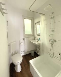 a white bathroom with a toilet and a sink at Gemütliche Ferienwohnung für bis zu 6 Personen im Stadtzentrum in Bremerhaven