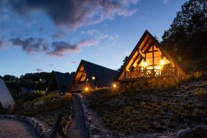 una casa de madera por la noche con luces encendidas en Chalets Na'Thur lodge en Fellering