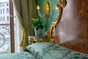 un letto con telaio dorato e una pianta accanto a una finestra di Hotel Marconi a Venezia