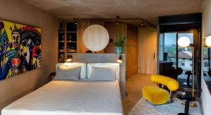 ein Schlafzimmer mit einem weißen Bett und einem gelben Stuhl in der Unterkunft Muchele Boutique Hotel in Burgstall