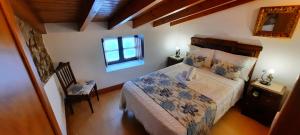 1 dormitorio con cama, ventana y silla en Casinha do México en Gondramaz