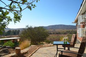 une table et des chaises sur une terrasse avec des montagnes en arrière-plan dans l'établissement Finca Jorsan, à Ensenada