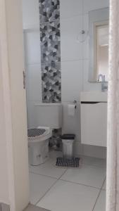 a white bathroom with a toilet and a sink at Costa do Encanto unidade Itapoa in Itapoa