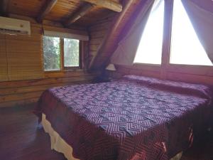 1 dormitorio con 1 cama en una habitación con ventanas en Las Terrazas Resort & Apart-Cabañas en La Falda