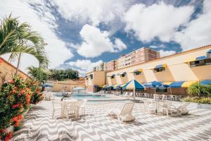 a resort pool with chairs and umbrellas at Hotel Triângulo in Caldas Novas