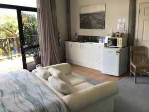 a bedroom with a bed and a kitchen with a microwave at Heads Up in Mangawhai
