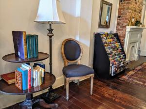a chair and a table with books and a lamp at Balcony Guest House in New Orleans