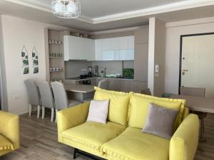 a living room with a yellow couch and a kitchen at Vlora Center Veranda in Vlorë