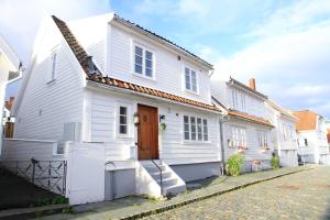 a white house with a wooden door on a street at Saga Caves Straen in Stavanger