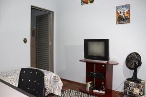 uma sala de estar com uma televisão e uma cadeira em Ecohouse - Próx da Av Brasil em Franca