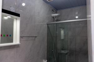 uma casa de banho com um chuveiro e uma porta de vidro em Hospedagem D´Roos em Canela