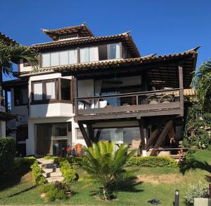 a large house with a balcony and a palm tree at Suite Independente Por do Sol Ferradura in Búzios