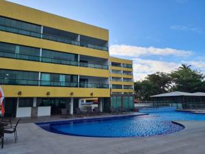 a building with a swimming pool in front of a building at Tabatinga Flat Beira Mar in Conde