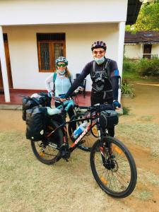 dos personas con máscaras de pie junto a una bicicleta en Kumari Guest House, en Polonnaruwa