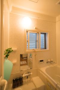 een badkamer met een wastafel, een bad en een raam bij ゲストハウス西金沢Smile&smile in Kanazawa