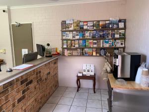 a room with a table, bookshelf and a microwave at Ulladulla Harbour Motel in Ulladulla