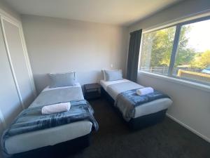 two twin beds in a room with a window at LINEA on Aorangi in Lake Tekapo