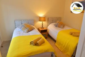 - une chambre avec 2 lits avec des draps jaunes dans l'établissement B and R Serviced Accommodation Amesbury, 3 Bedroom House with Free Parking, Super Fast Wi-Fi 145Mbs and 4K smart TV, Archer House, à Amesbury