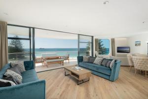 a living room with blue furniture and a view of the ocean at Oceanside Haven Resort with Luxury Sea Views in Mount Maunganui