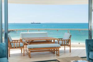 a table and chairs with a view of the ocean at Oceanside Haven Resort with Luxury Sea Views in Mount Maunganui