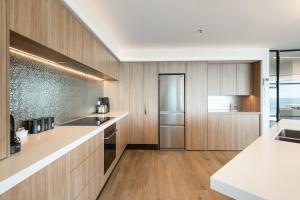 a kitchen with wooden cabinets and white counter tops at Oceanside Haven Resort with Luxury Sea Views in Mount Maunganui