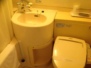 a small bathroom with a sink and a toilet at Asano Hotel in Kitakyushu